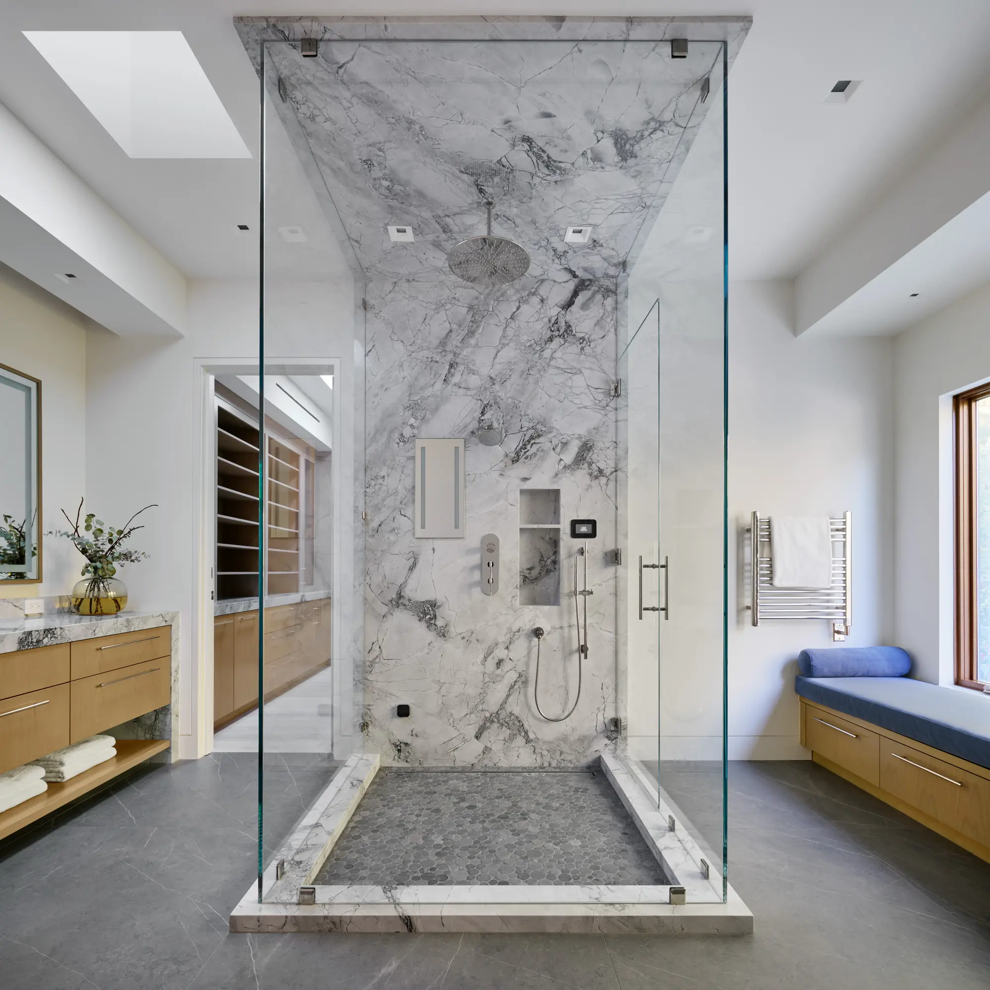 Freestanding glass shower with floor-to-ceiling marble walls, rainfall showerhead, and skylight in modern bathroom