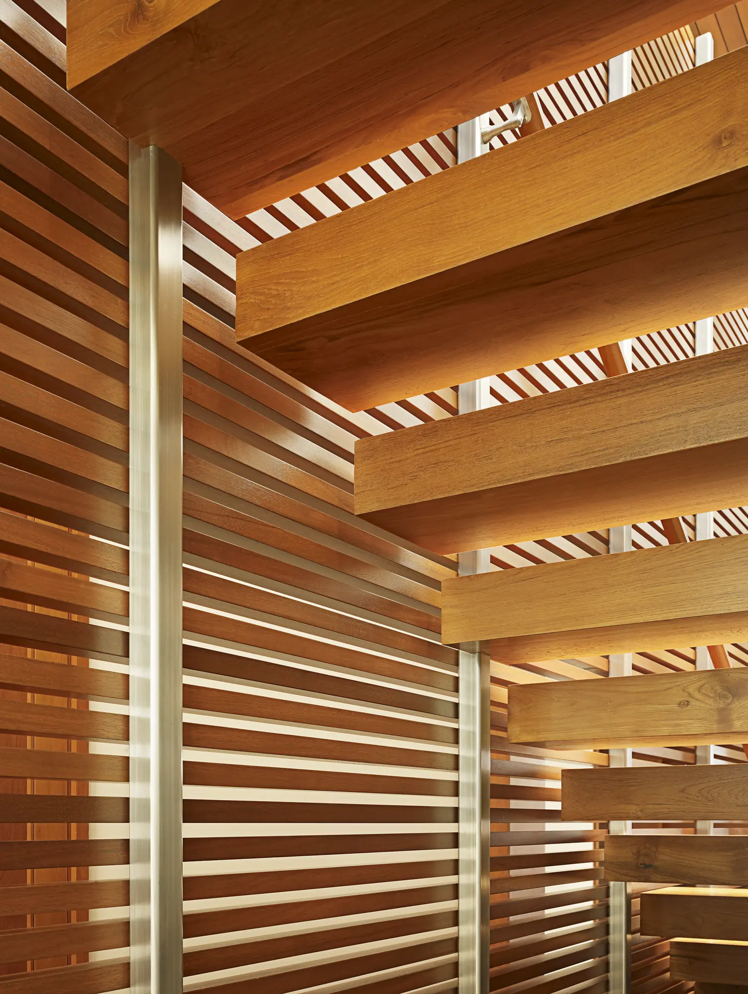 Warm wood slat ceiling and walls with metal columns, creating layered geometric patterns and natural light play.