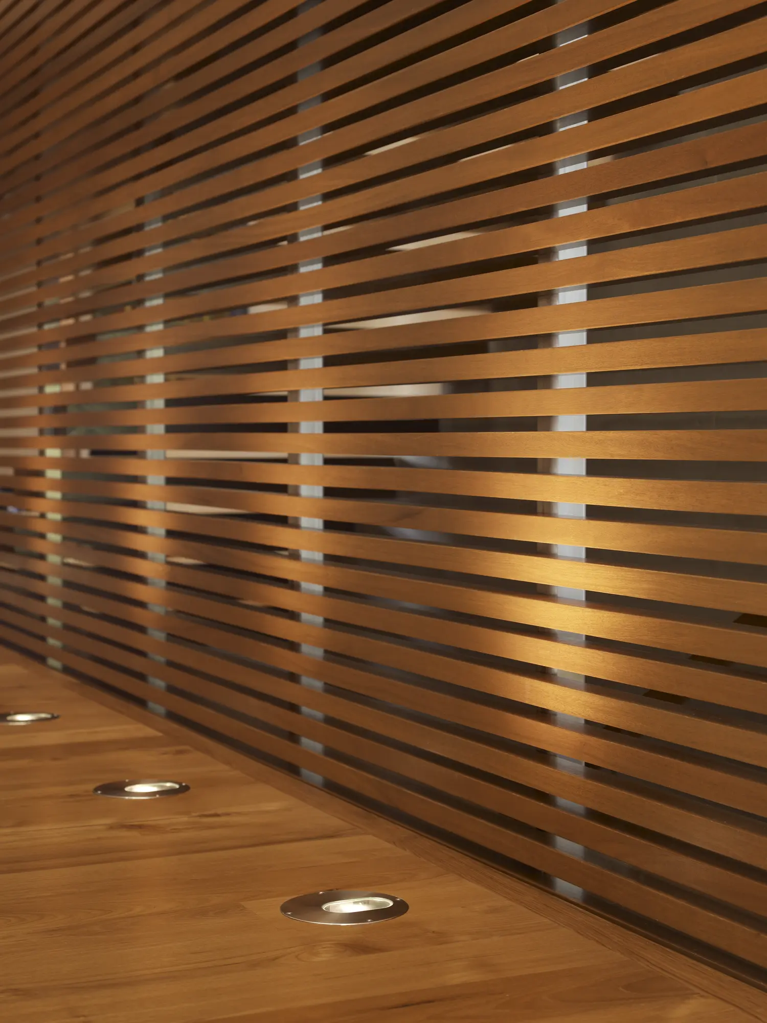 Horizontal cedar slats with gaps on wall and ceiling, with recessed floor lighting in wooden deck
