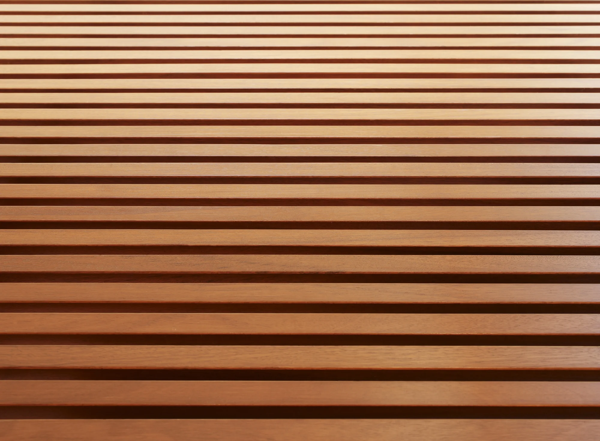 Close-up of horizontal wood slats in varying warm tones, showcasing natural grain and craftsmanship detail.