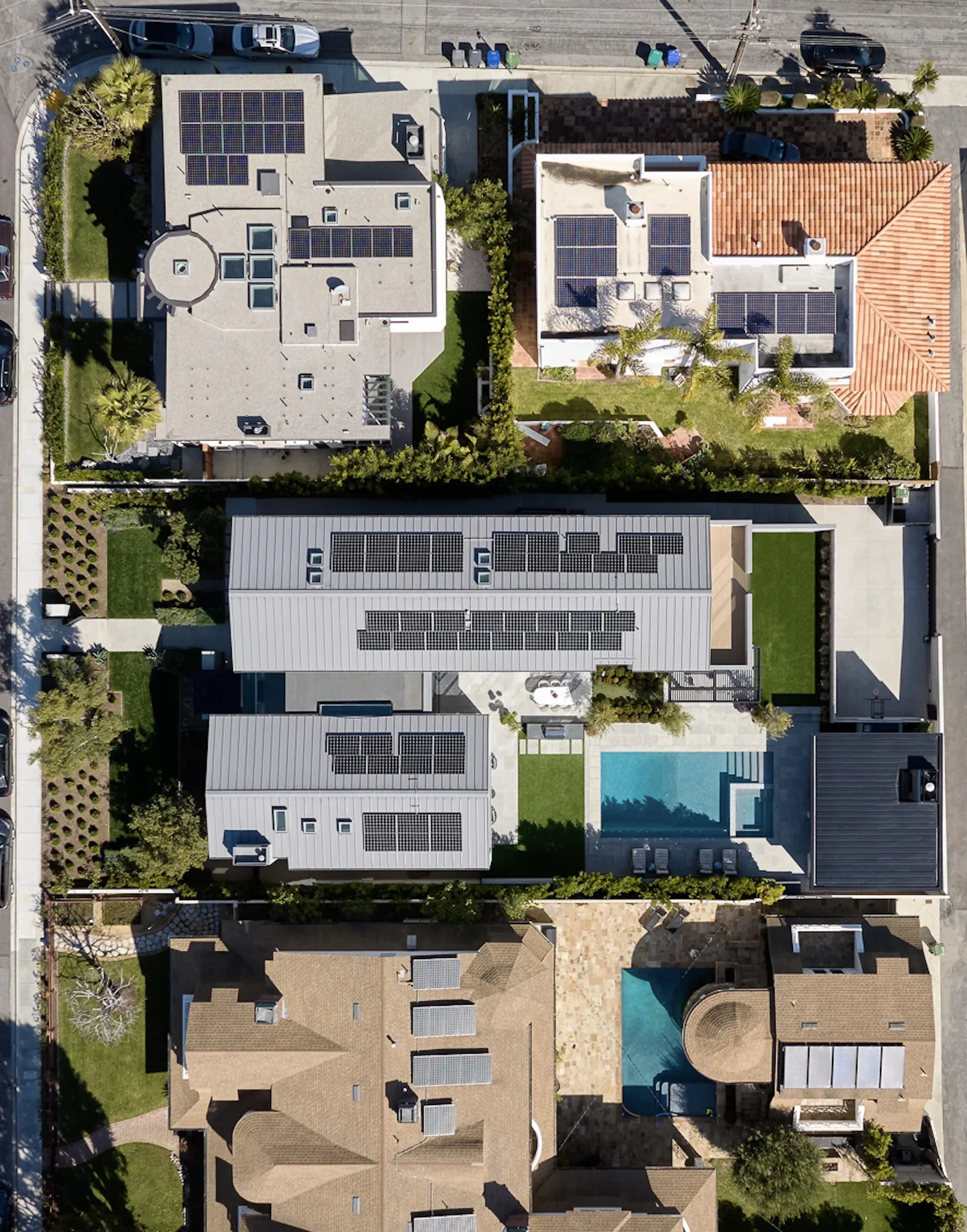 Aerial view of modern residential homes with extensive solar panel installations on flat and sloped rooftops